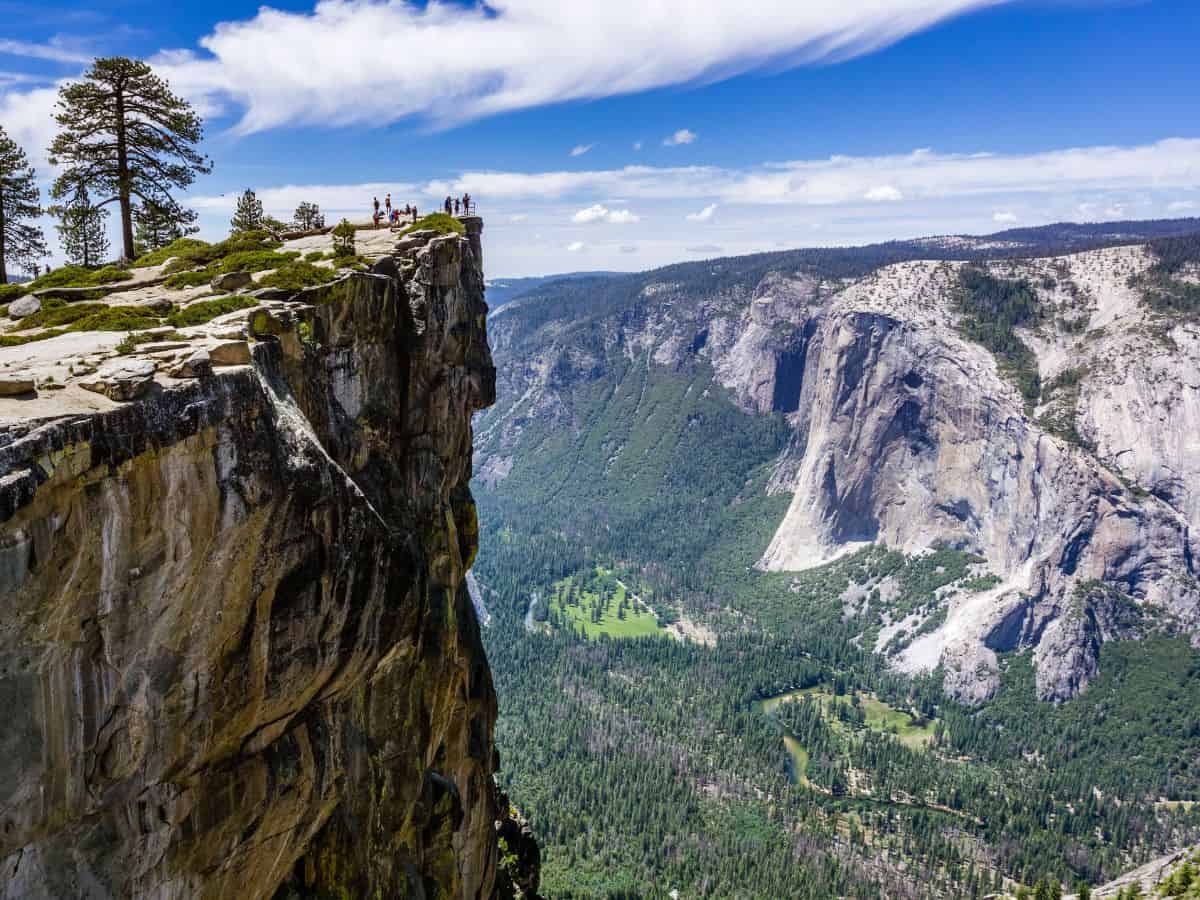 A dramatic view of Yosemite Valley from the edge of Taft Point, where visitors stand on the cliff's edge, making it one of the 29 best viewpoints in Yosemite.