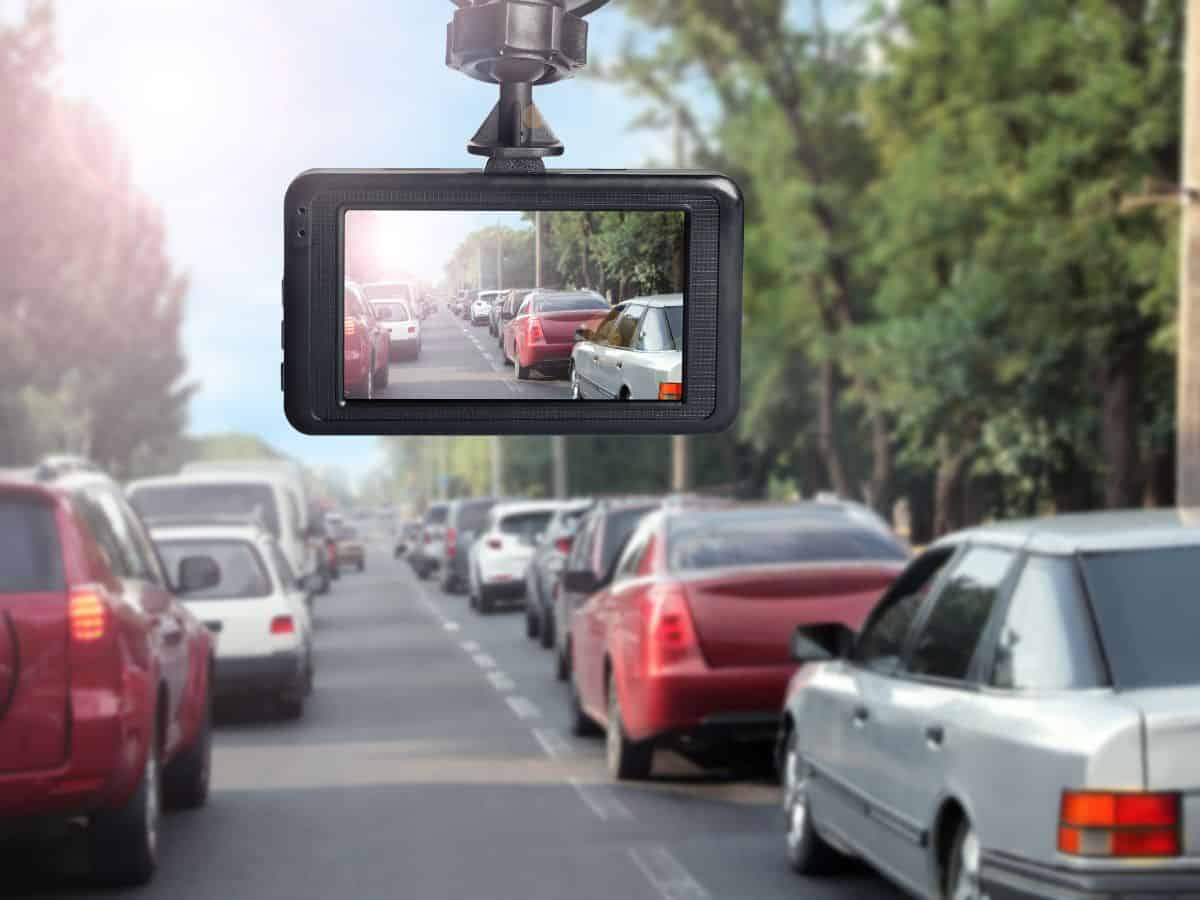 A dashcam recording traffic on a busy road, mounted inside a car. This device is a useful part of any California packing list to capture your road trip memories and ensure safety.