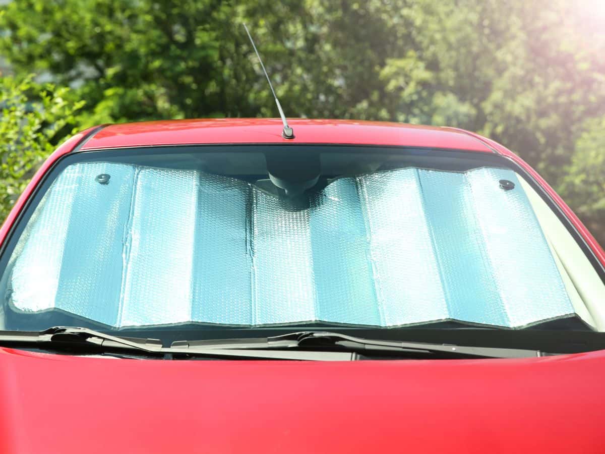 A car windshield sun shade installed on the front window of a red car, protecting the interior from the harsh California sun. A practical item on your California packing list to keep your vehicle cool.