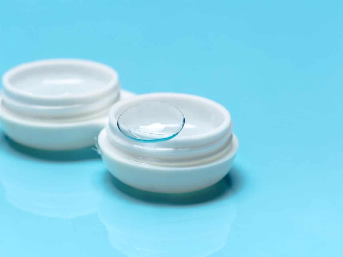 A contact lens case filled with solution, with one lens placed on the edge, an important item on the California Packing List for maintaining eye care on the go.