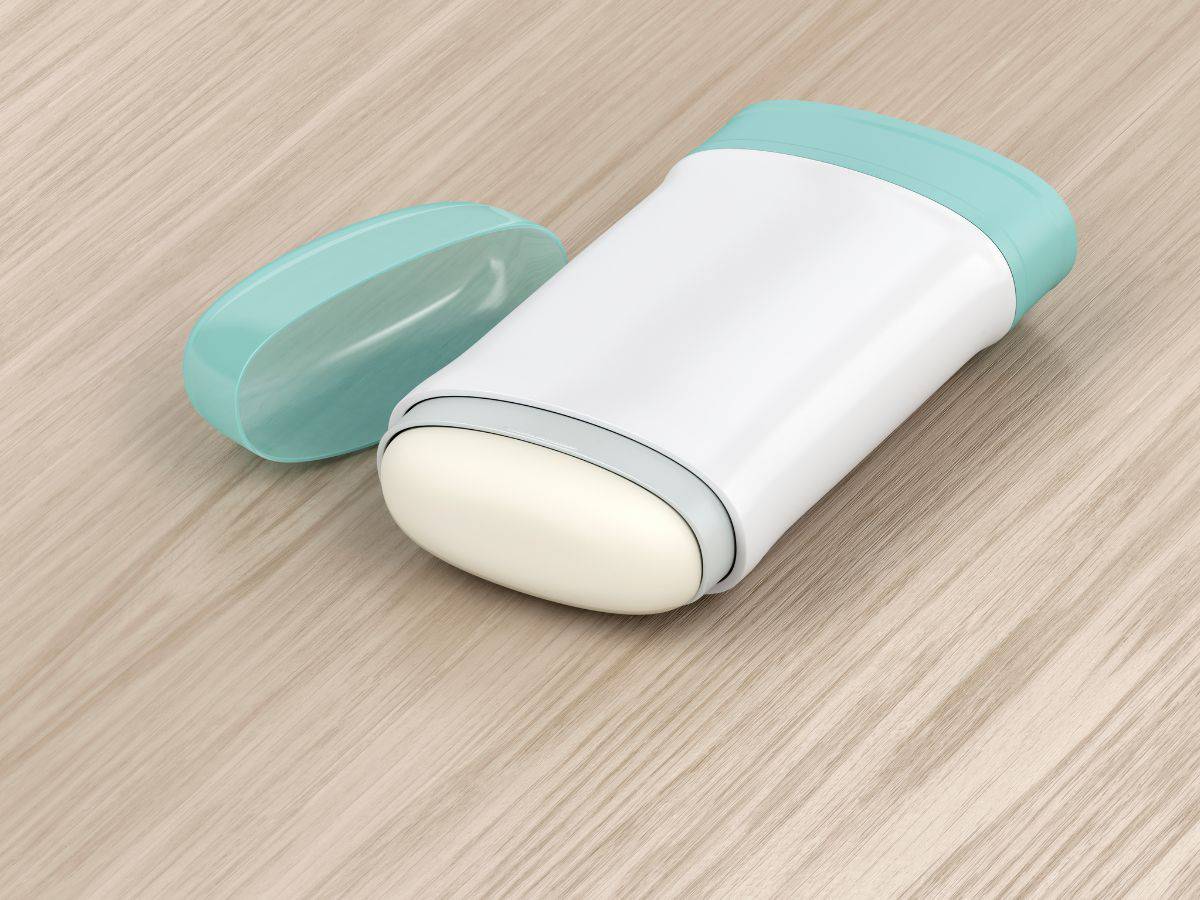  A travel-sized deodorant stick with a turquoise cap lying on a wooden surface, ideal for a California Packing List to stay fresh during outdoor activities.