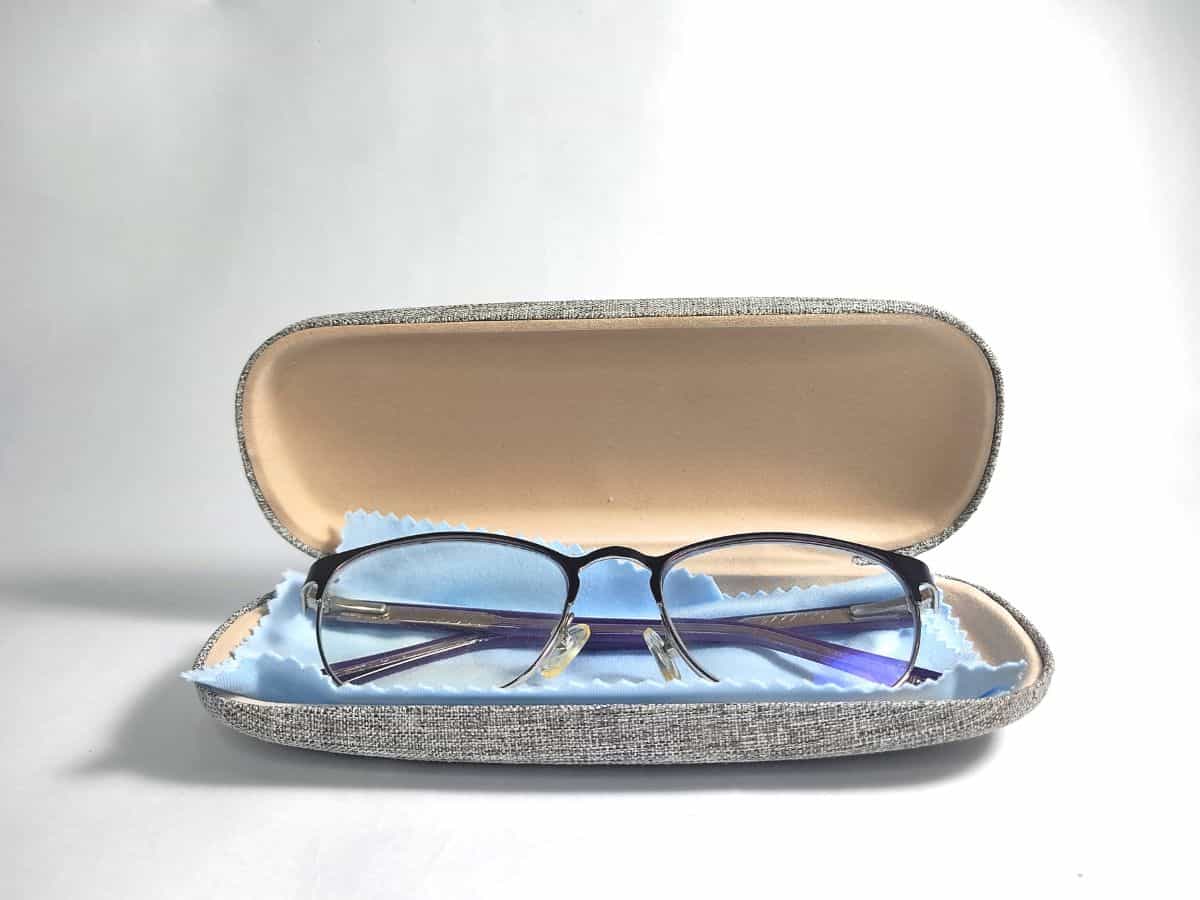 A pair of eyeglasses placed inside an open case with a cleaning cloth, essential for the California Packing List to keep eyewear safe during travels.