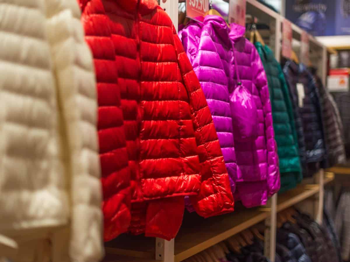 A row of colorful puffer jackets on display in a store, highlighting the need to include a warm jacket in your California packing list for cooler evenings.