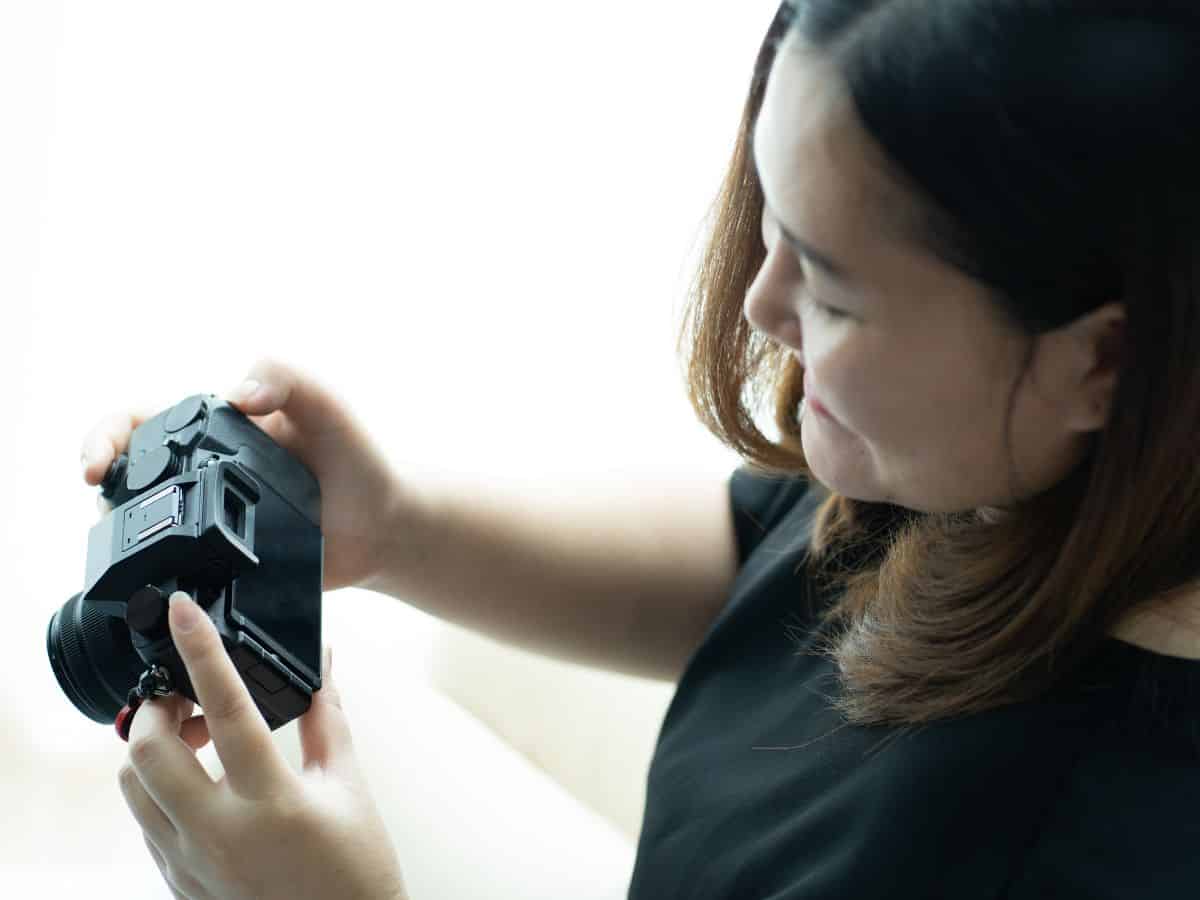 A person holding and examining a mirrorless digital camera. Adding a reliable digital camera to your California packing list ensures you capture high-quality memories during your trip.

