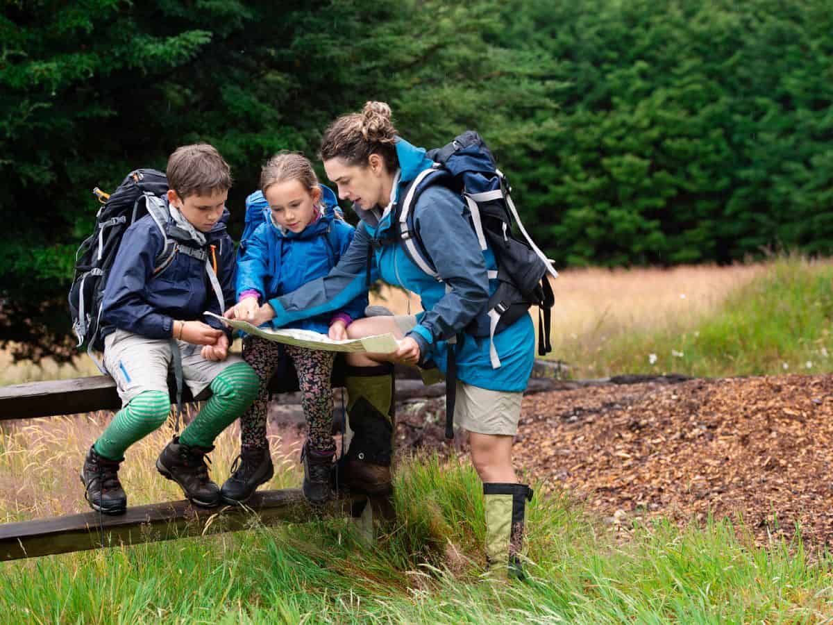 A family looking at a park map while wearing hiking gear, perfect for exploring California’s national parks. A national parks pass and map are useful additions to your California packing list if you plan on hiking or exploring natural reserves.
