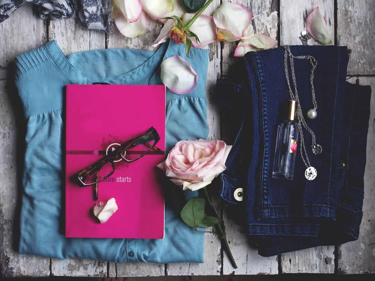 An assortment of neatly folded clothing items including a stylish top, jeans, and accessories, perfect for dressing up your California packing list with one or two pieces of fancy wear.