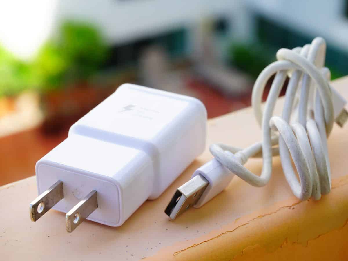 A phone charger with a coiled cable placed on a ledge with a blurred background. Don’t forget to include a phone charger in your California packing list to stay connected on the go.