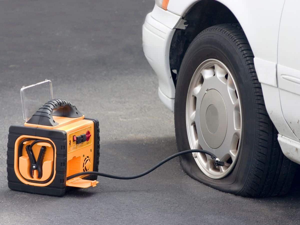 A portable air compressor inflating a flat tire on a car. This handy tool is an essential addition to your California packing list to ensure you're prepared for any tire issues.