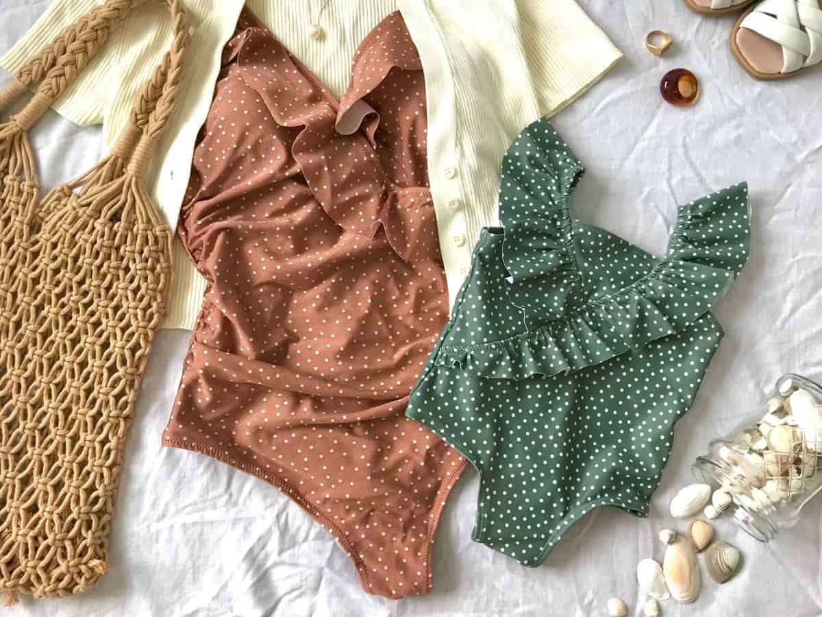 A flat lay of two polka-dotted swimsuits, one brown and one green, along with a macrame beach bag and other accessories. Including versatile swimwear is a must on your California packing list for enjoying the beach or pool.