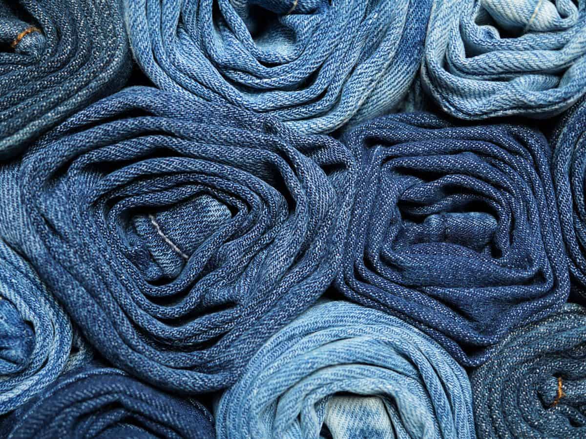 A tightly rolled collection of blue jeans, representing the essential inclusion of two to three pairs of pants in your California packing list.