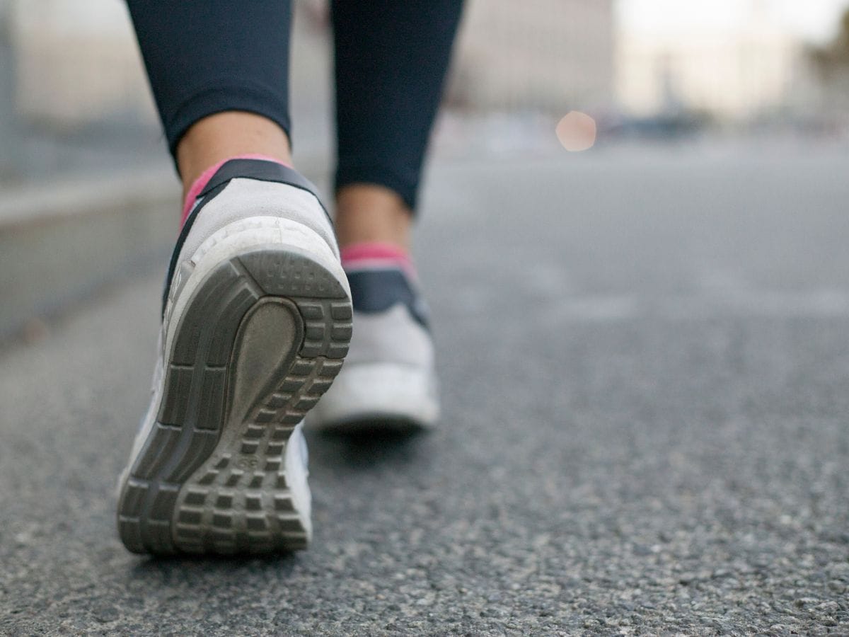 Close-up image of a person wearing walking shoes on a paved road, emphasizing the importance of comfortable footwear in a California packing list.