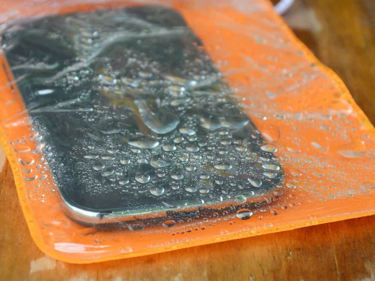 A smartphone inside a waterproof case, covered in water droplets. Perfect for beach trips, a waterproof phone case is a recommended item on your California packing list.