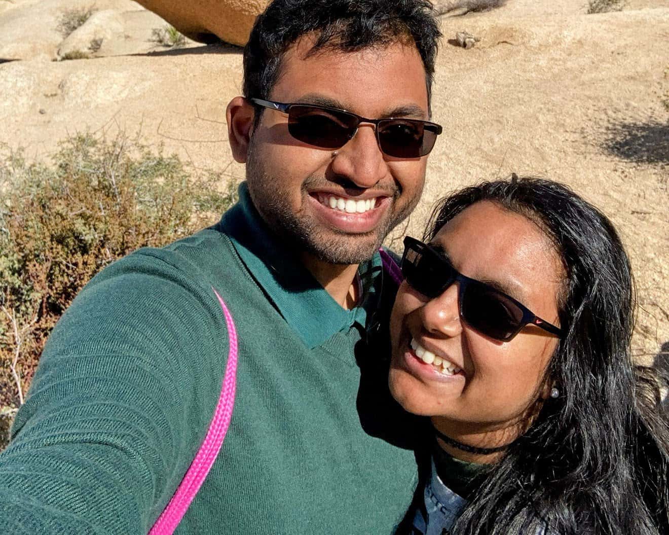 Kiran and Shreeyeh taking a selfie in the bright desert sun, surrounded by the rocky terrain of Joshua Tree National Park.