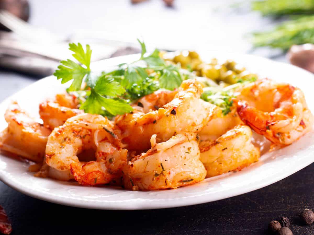 A plate of juicy, grilled shrimp garnished with fresh parsley and served with a side of vegetables, exemplifying the flavor-packed offerings of Best Seafood In Southern California. The perfectly seasoned shrimp adds a delightful touch to any seafood lover’s meal.