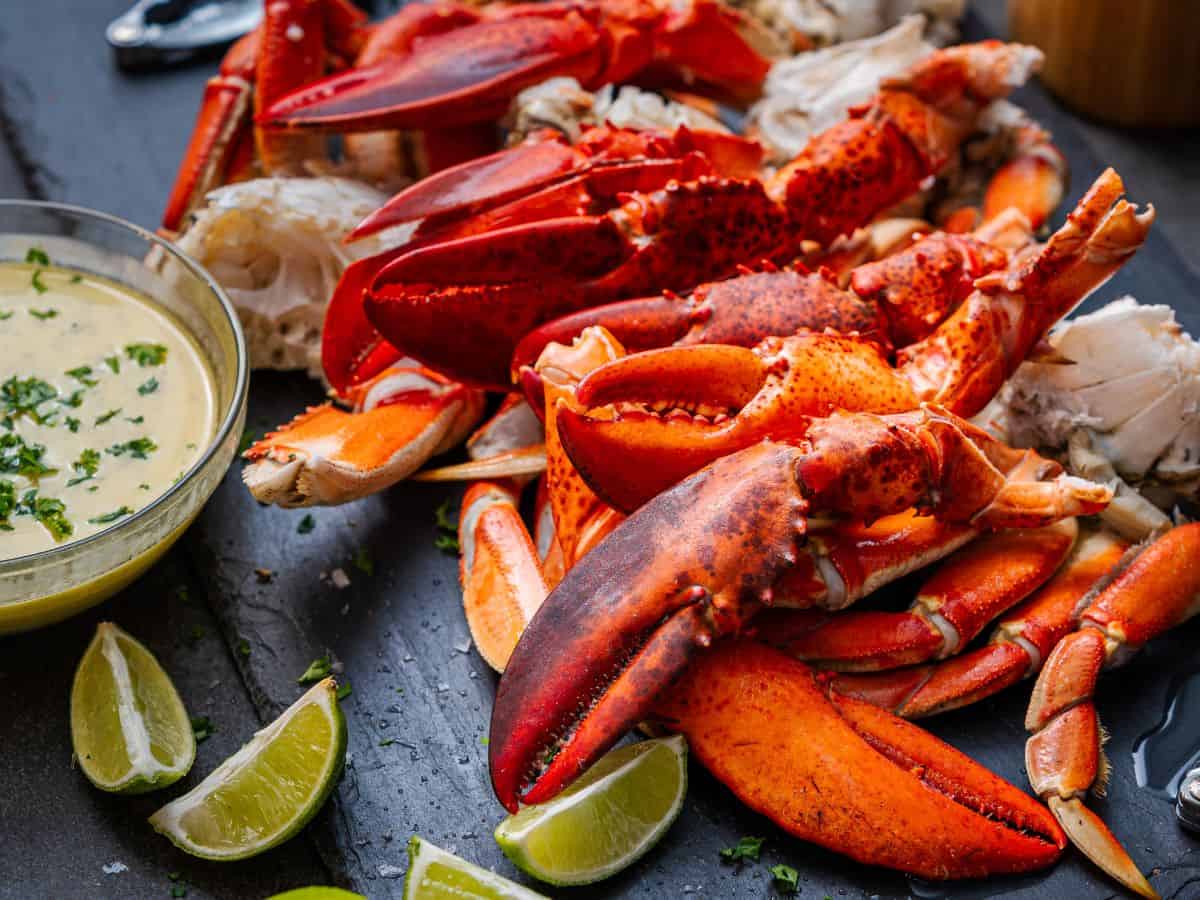 A generous platter of lobster claws and meat, served with lime wedges and a creamy dipping sauce, offering a fresh and flavorful experience from the Best Seafood In Southern California. A perfect feast for seafood lovers.