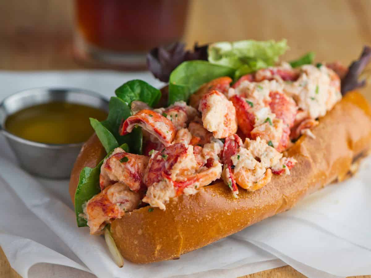  A lobster roll filled with fresh lobster meat, lettuce, and herbs, representing the classic flavors of Best Seafood In Southern California. This simple yet elegant dish highlights the freshness and richness of the lobster.