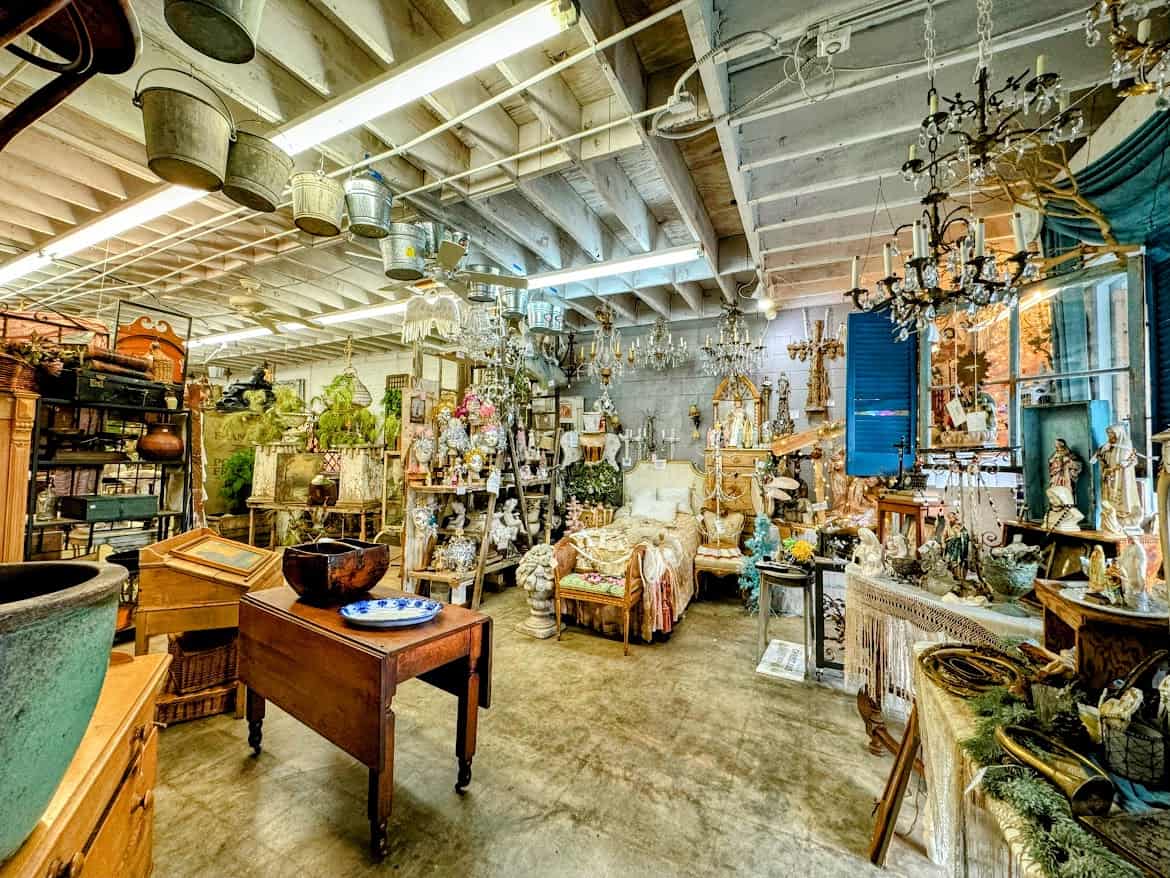 The charming interior of Vignettes Antiques & Collectibles, filled with vintage furniture, chandeliers, and decorative items arranged in a whimsical and cozy style.
