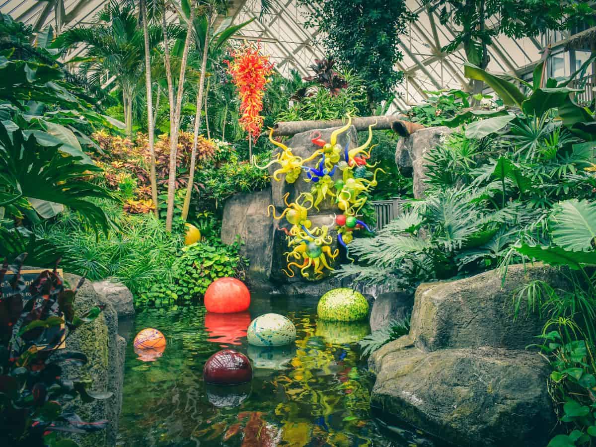 A vibrant indoor garden featuring colorful glass sculptures and lush greenery, reflecting Seattle’s focus on outdoor experiences in contrast to the entertainment-oriented vacations in Los Angeles in the Seattle vs Los Angeles comparison.