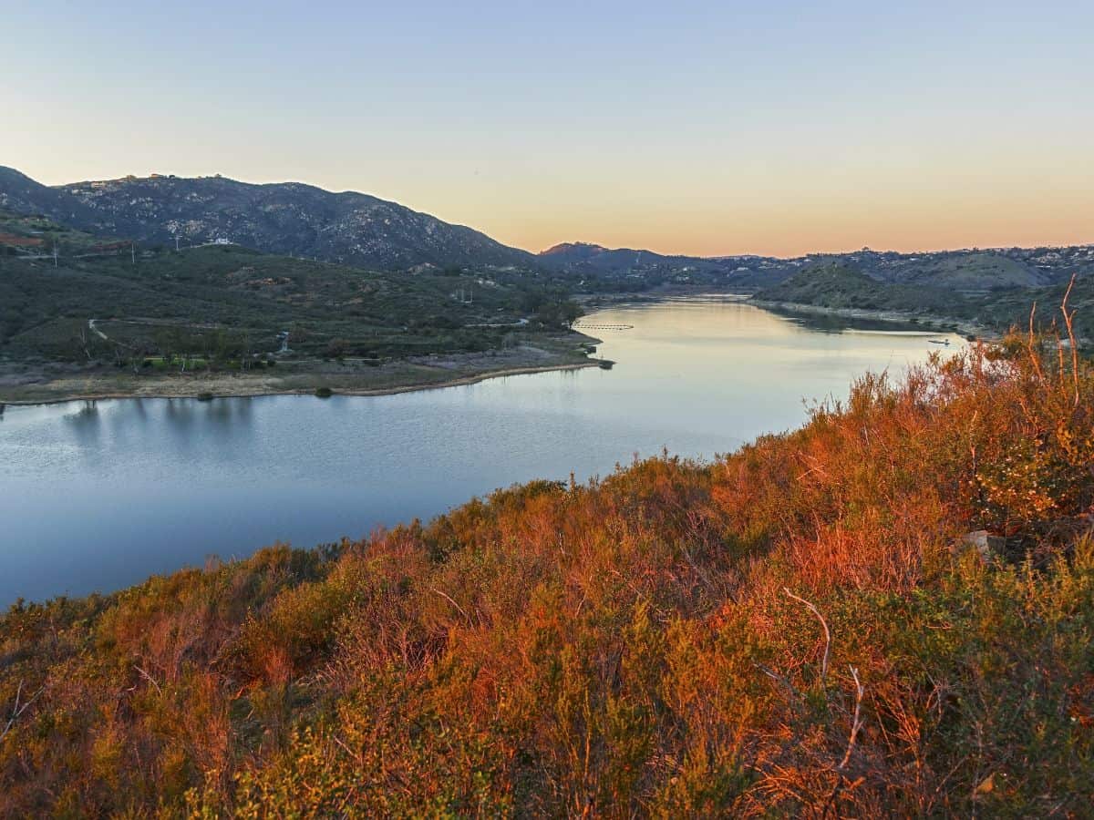 Lake Hodges Trail features calm waters reflecting the surrounding hills at sunset, a serene and scenic choice for dog-friendly hikes in San Diego.