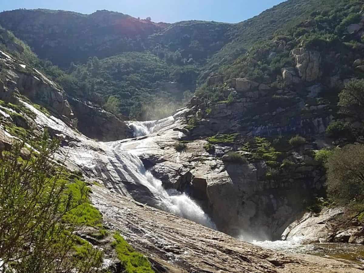 Three Sisters Falls cascades down rocky terrain surrounded by lush greenery, making it a picturesque spot for dog-friendly hikes in San Diego.