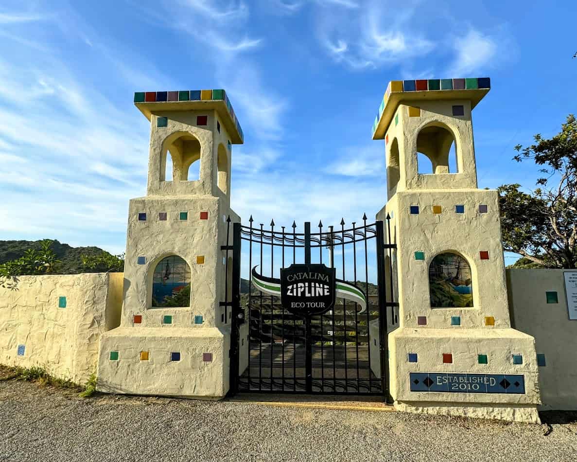 The vibrant, colorful entrance gate to the Catalina Zipline Eco Tour, flanked by two decorative towers with mosaic patterns, set against a bright blue sky.