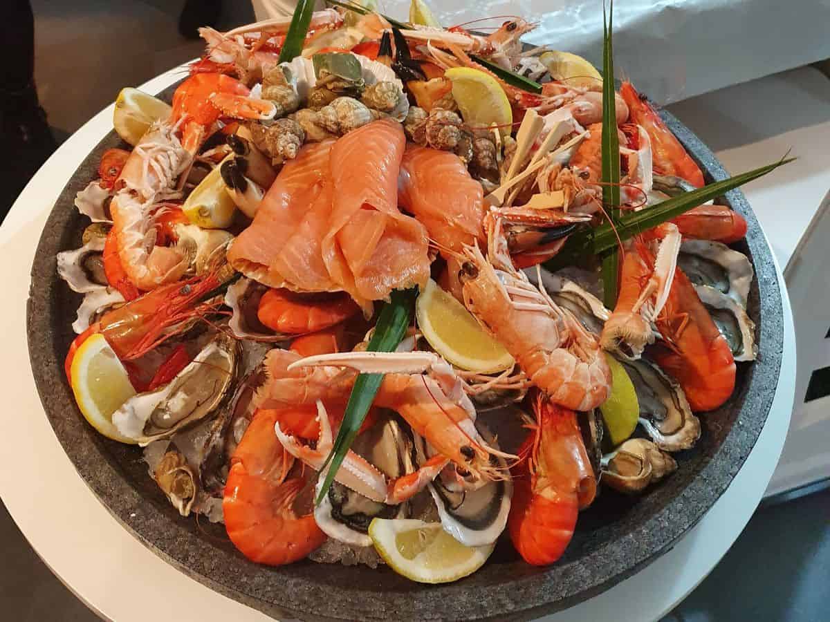 A seafood platter featuring fresh shrimp, salmon, oysters, and shellfish garnished with lemon slices and herbs. This image represents Miami's culinary scene, known for its fresh seafood, offering a comparison point against Los Angeles.