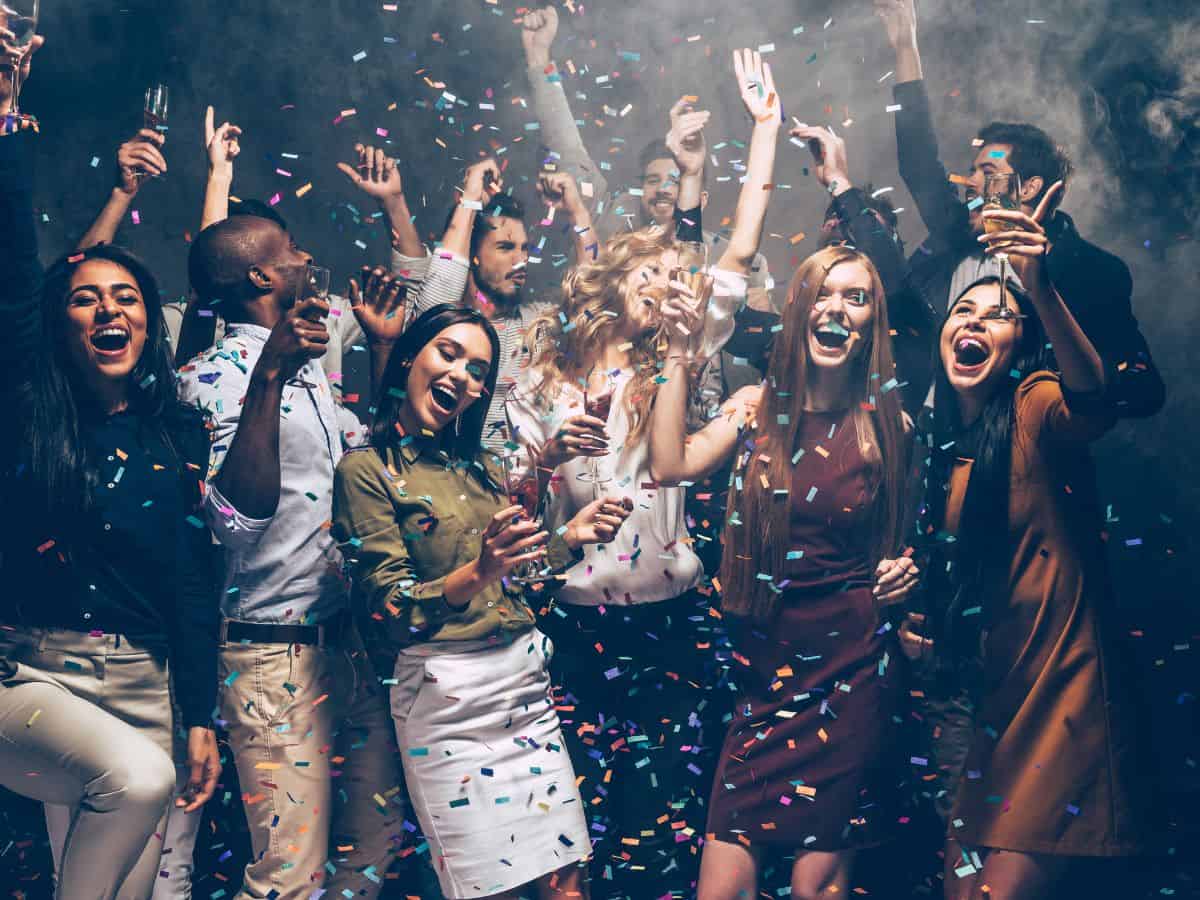 A group of people celebrating in a lively party atmosphere with confetti and drinks, representing the nightlife scenes in Denver vs San Francisco. The image conveys excitement, fun, and social gatherings.