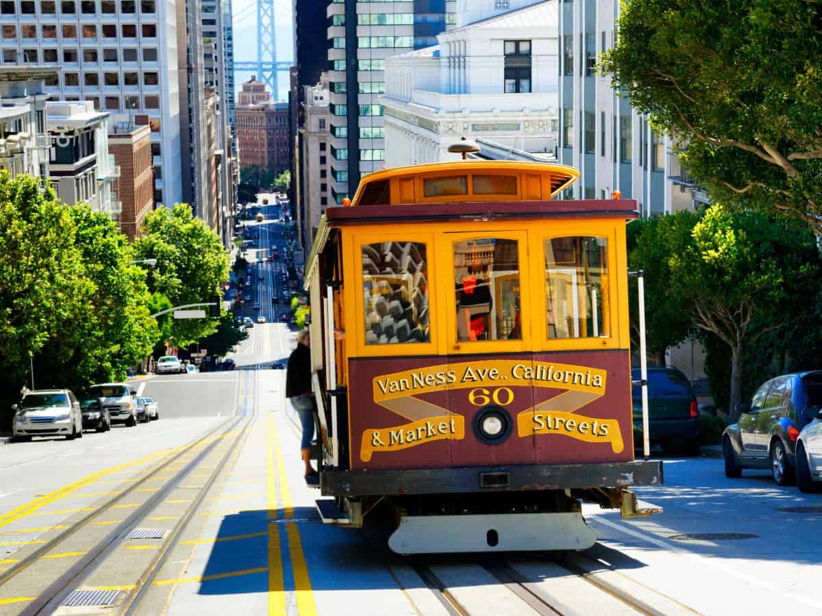 A classic San Francisco cable car making its way up a steep street, symbolizing public transportation options in San Francisco vs Denver. The image showcases the city's unique and historic transit system.