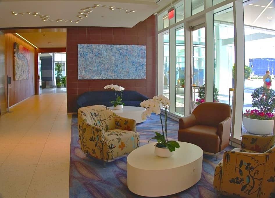 A chic and welcoming lobby area with sleek furnishings and modern art pieces, bathed in natural light from large windows, offering a tranquil and stylish space for relaxation or informal meetings.