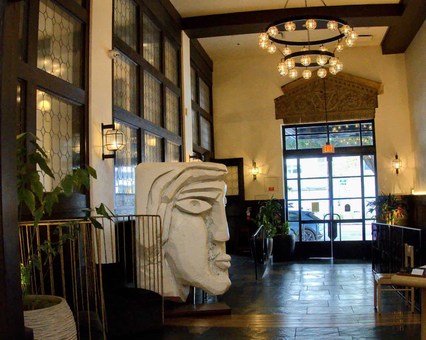 The grand lobby of Hotel Figueroa in Los Angeles, with elegant chandeliers, artistic decor, and a welcoming ambiance.