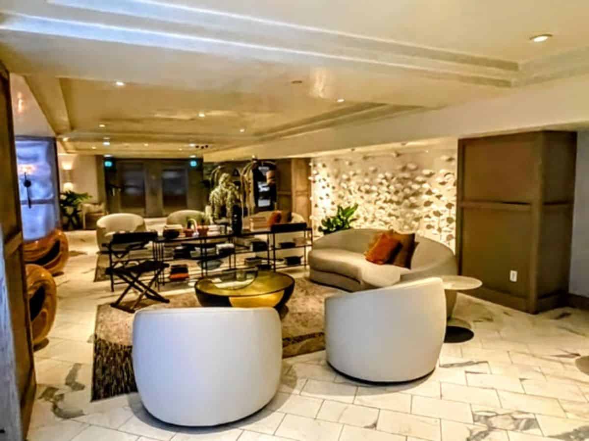 A serene and stylish guest room at The Huntley Hotel in Los Angeles, featuring a luxurious bed, chic decor, and natural light streaming through large windows.