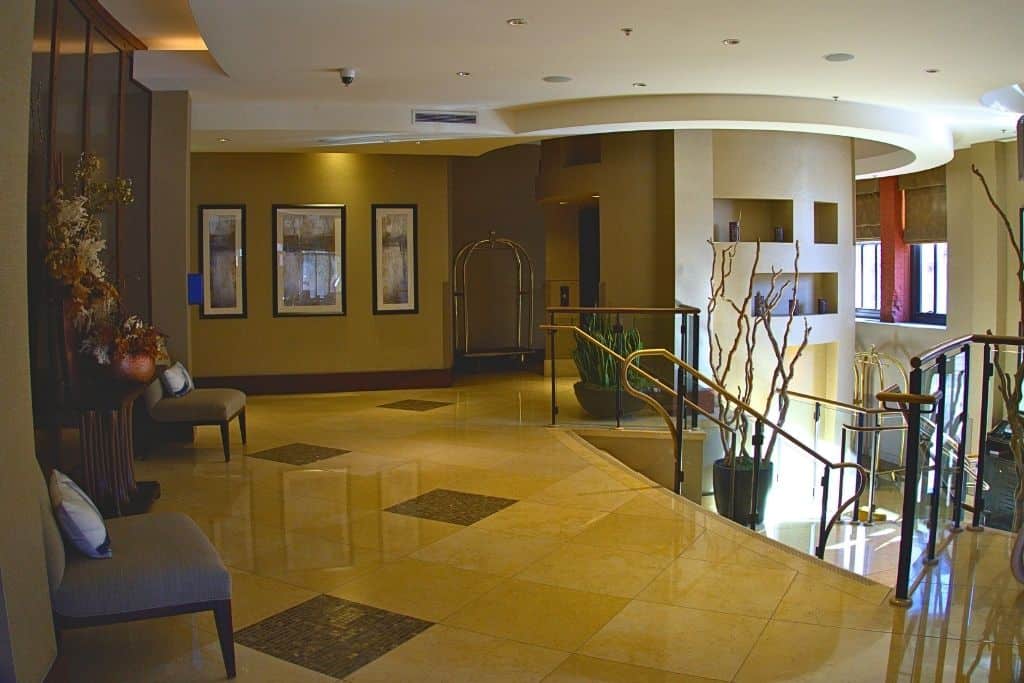 A lounge area with contemporary furniture, including sofas and chairs around a central coffee table, with a lamp stand on either side, and decorative vases adding to the ambiance.