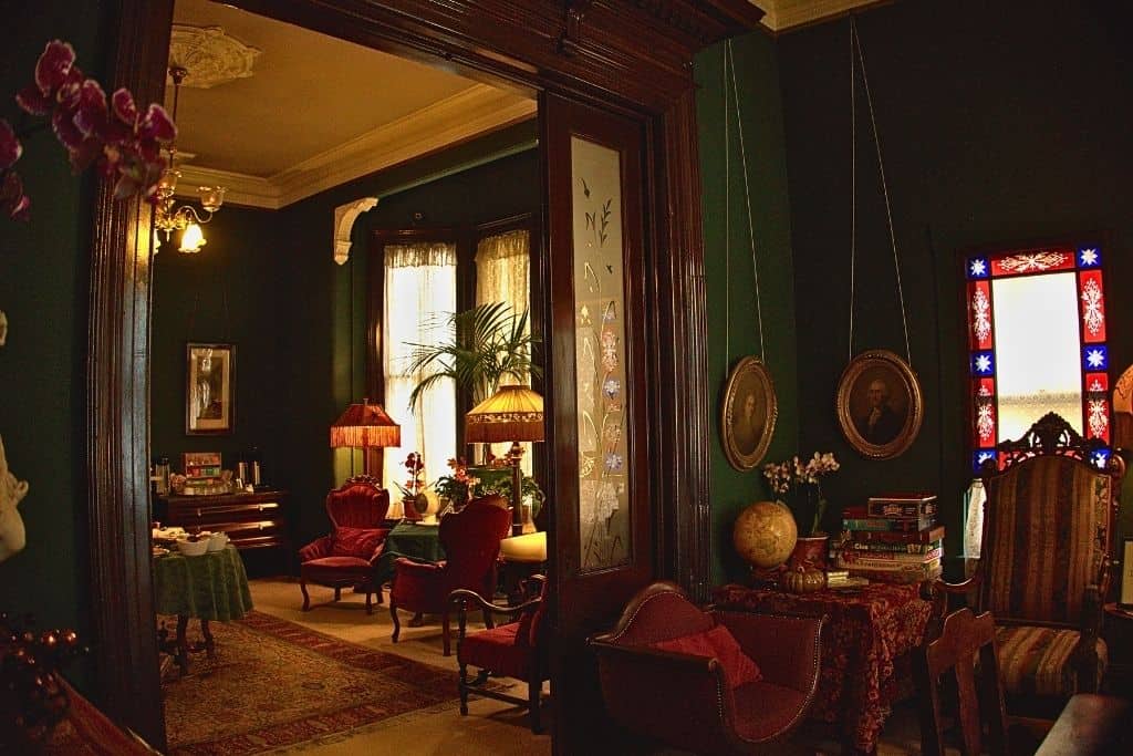 A vintage-inspired living room with vibrant stained glass, rich green walls, and antique furnishings, creating a warm and nostalgic ambiance.