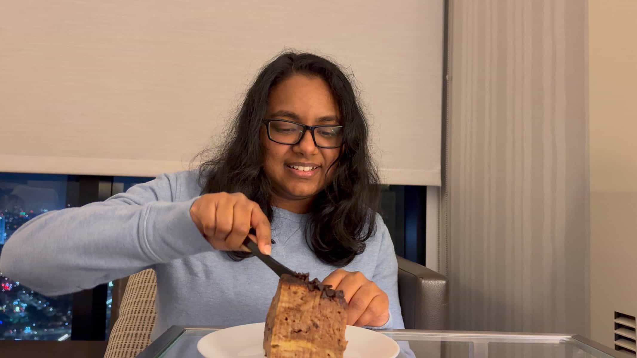 Shreeyeh is cutting into a rich, chocolate-topped French Pudding from Parfait Paris Gaslamp Quarter to celebrate her birthday.