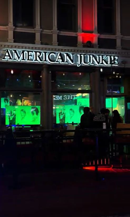 The neon sign of American Junkie glowing at night, a popular spot among the best bars in Gaslamp Quarter San Diego, with people hanging out front
