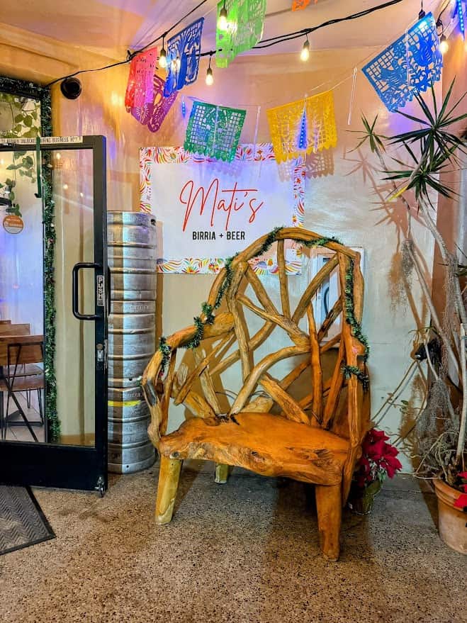 Inside Matis, a charming inclusion among the best restaurants in Pacific Beach San Diego, with colorful papel picado banners overhead and a rustic wooden chair in the foreground