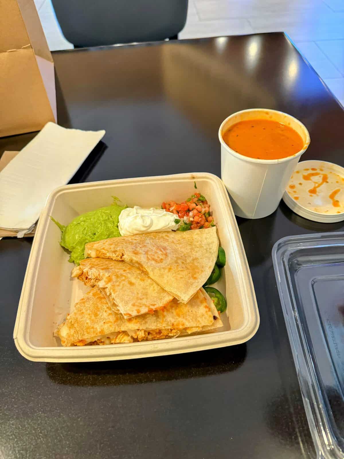 A cut-up quesadilla topped with shredded cheese and side servings of guacamole and sour cream at Market One, one of the best Seaport Village restaurants