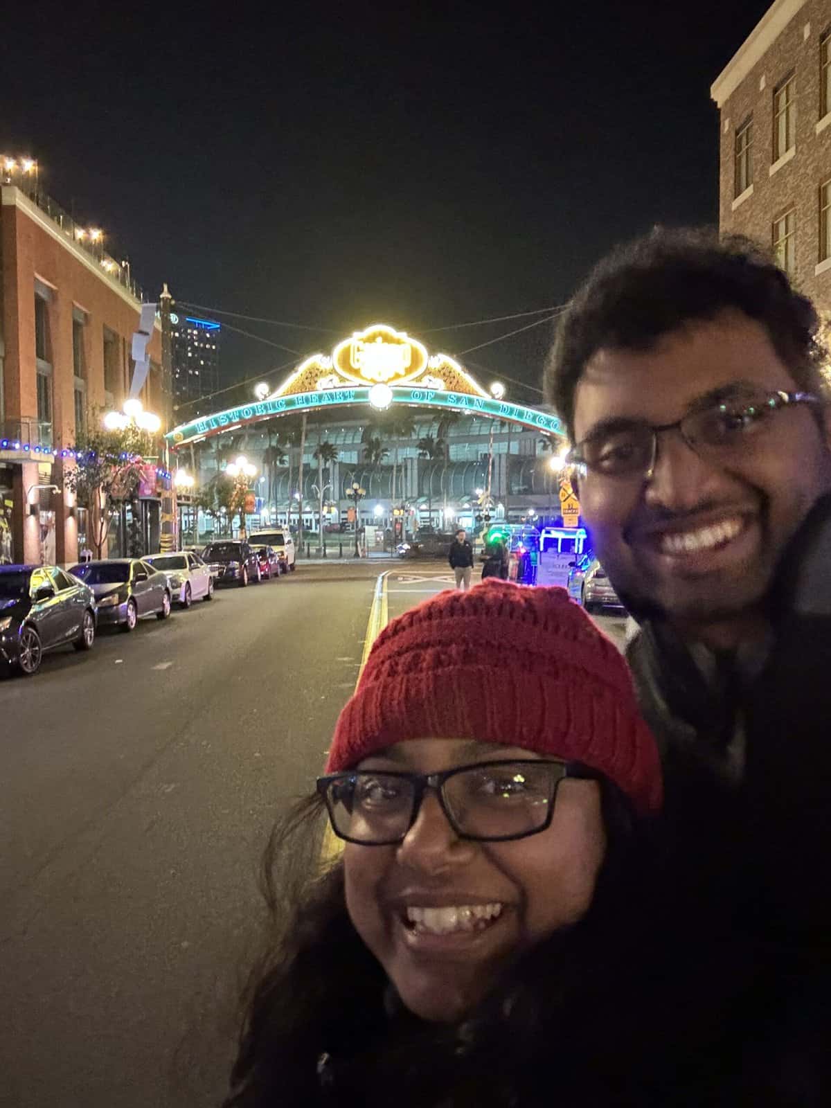 A smiling couple taking a selfie with the neon-lit Gaslamp Quarter sign in the background, a top thing to do in Gaslamp Quarter.