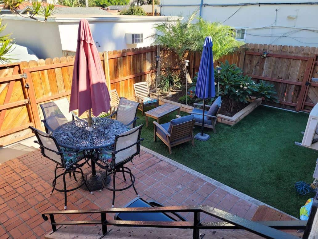 Charming outdoor dining area in the garden of one of the best Airbnbs in Ocean Beach San Diego, featuring a detailed mosaic table and surrounded by vibrant plants