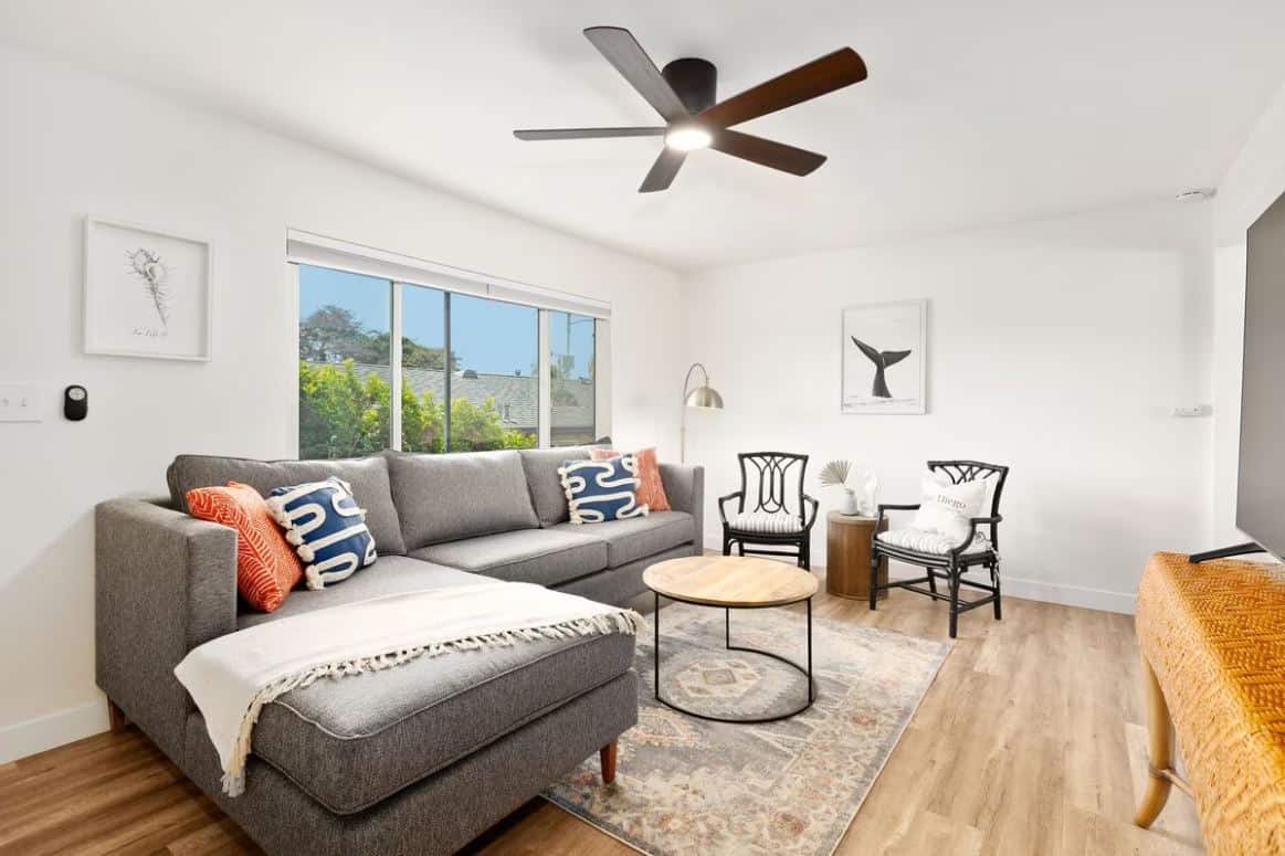 Modern living room area inside a sought-after Airbnb in Ocean Beach San Diego, featuring a sleek design with a plush gray couch, elegant black and white armchairs, and a contemporary round coffee table