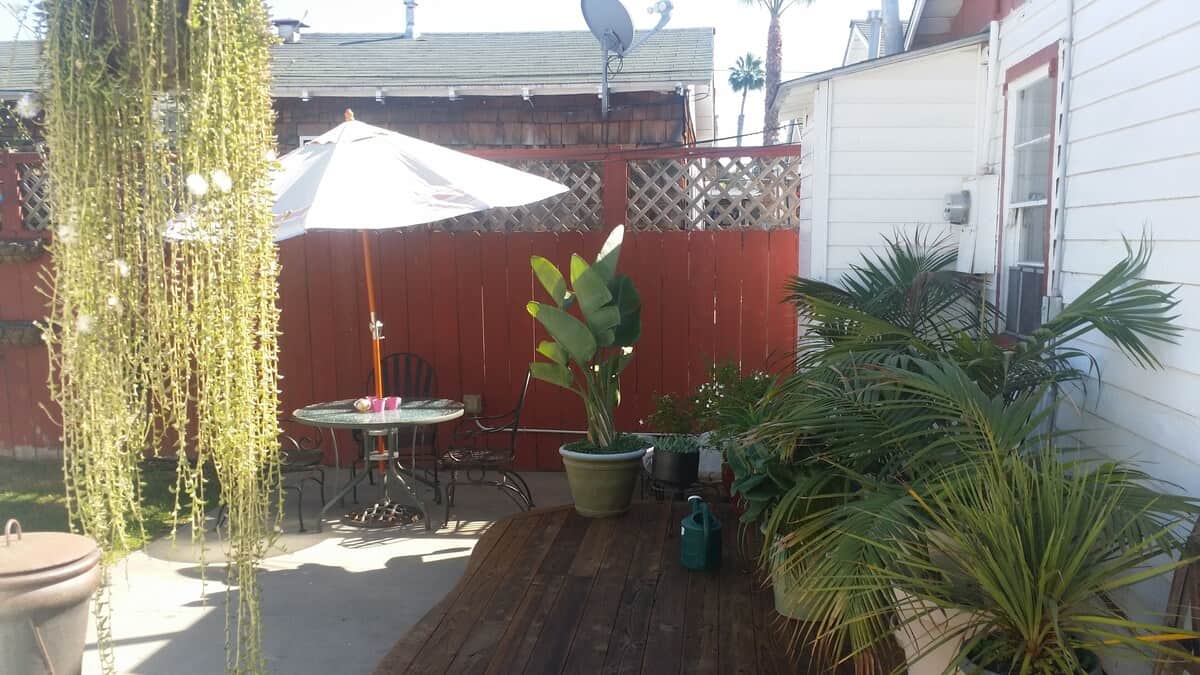 Secluded and tranquil backyard patio at one of the best Airbnbs in Ocean Beach San Diego, surrounded by lush greenery and equipped with comfortable outdoor furniture under a shaded umbrella