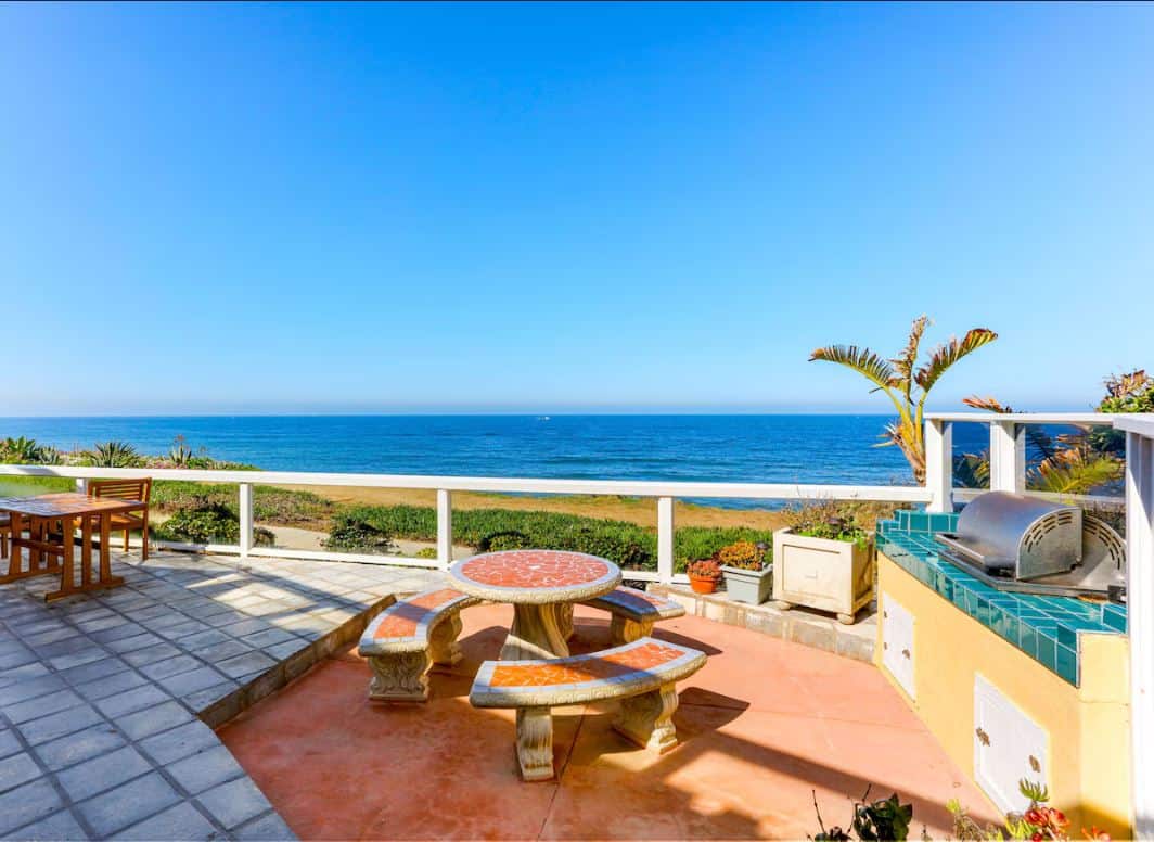 Stunning patio area overlooking the ocean at one of the best Airbnbs in Ocean Beach San Diego, complete with a stone table and lush potted plants