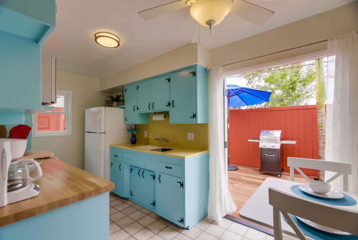 Colorfully decorated kitchen in one of the best Airbnbs in Ocean Beach San Diego, with bright blue cabinetry and a direct view into a private patio