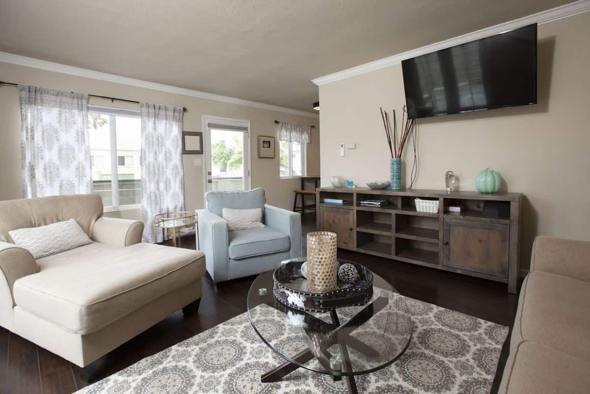 Modern living room area inside a sought-after Airbnb in Ocean Beach San Diego, featuring a sleek design with a plush beige couch, elegant armchairs, and a contemporary glass coffee table
