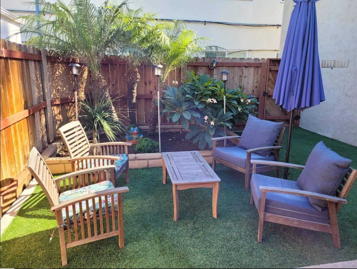 Charming garden patio area at one of the best Airbnbs in Ocean Beach San Diego, equipped with comfortable seating, lush greenery, and a vibrant blue umbrella