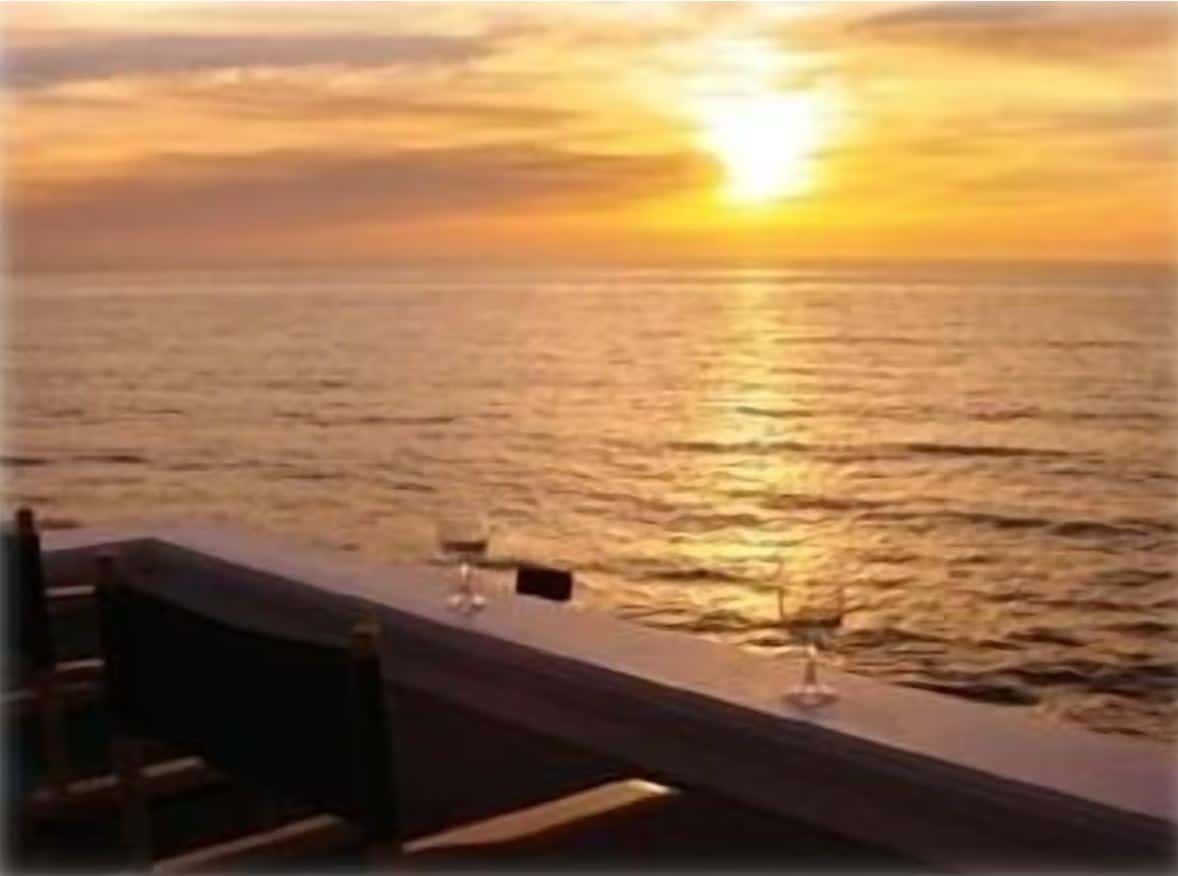 Sunset view from a balcony at one of the best Airbnbs in Ocean Beach San Diego, featuring a romantic setting with wine glasses overlooking the ocean