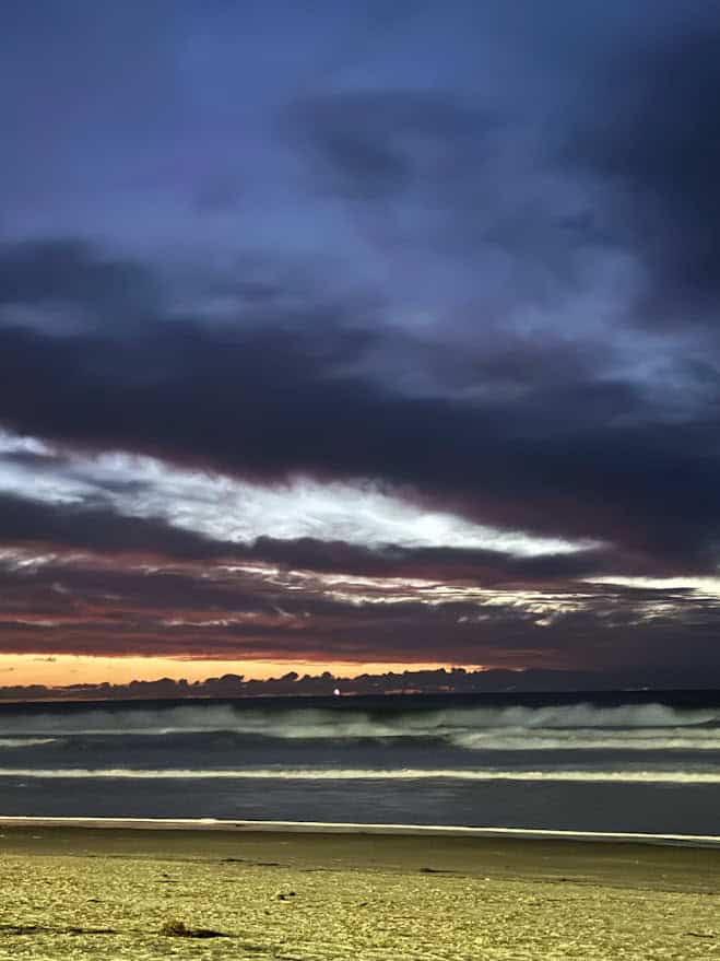 A stunning sunset over the ocean at Mission Beach, with waves gently crashing onto the shore, offering a serene experience and one of the relaxing things to do near Belmont Park.