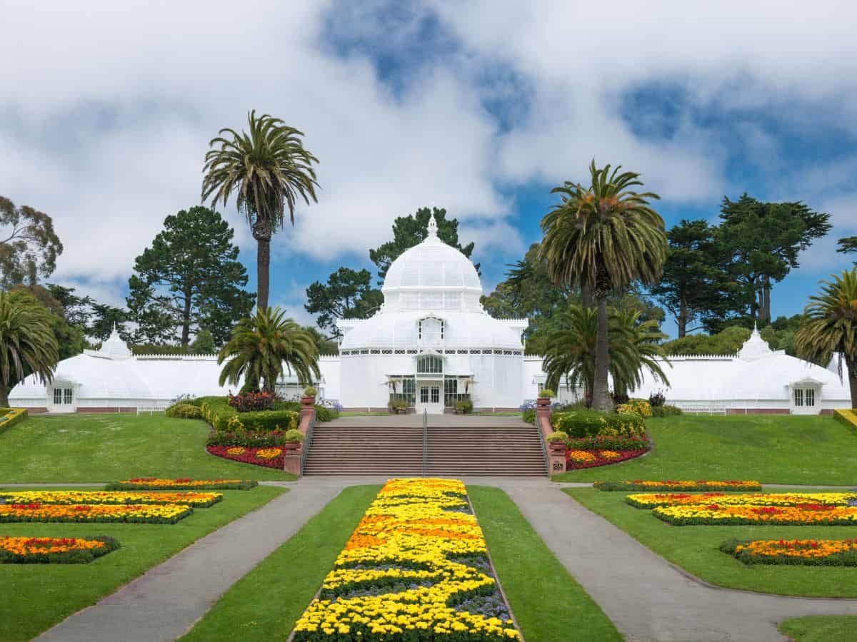 The iconic Conservatory of Flowers in San Francisco's Golden Gate Park, showcasing its distinctive white facade and structural elegance amidst lush floral displays. It stands as a historical landmark and a top pick for things to do in San Francisco.