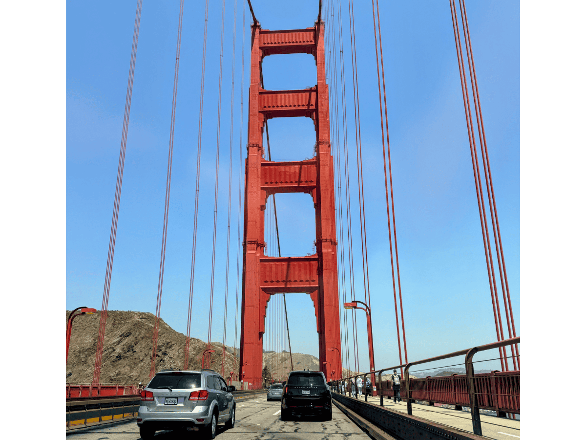 Point of view driving through the Golden Gate Bridge with cars in front and the Marin Headlands in the background