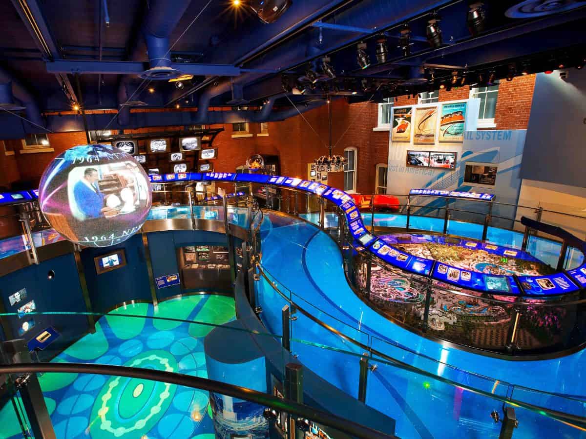 An interior view of The Walt Disney Family Museum, a must-see attraction among things to do in San Francisco. The museum features vibrant displays, including a large spherical screen projecting images from Disney history, interactive exhibits, and a circular walkway overlooking detailed models. The modern design and multimedia presentations provide an immersive experience for visitors interested in the life and legacy of Walt Disney.